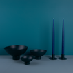 A trio of footed bowls and pair of candle holders, all in Peacock, with blue taper candles.
