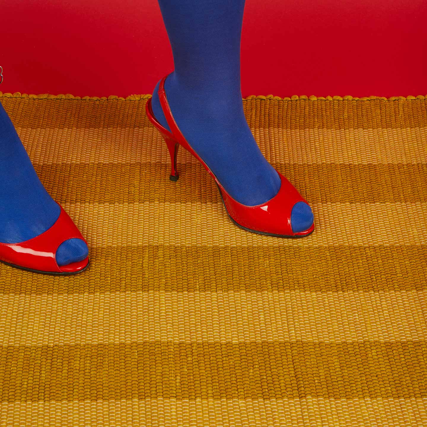 Red high-heeled shoes with blue toes Essential Floor Runner in Mustard with red background.