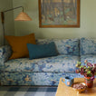 Living room with a floral-patterned sofa, decorative pillows, and a painting on the wall.