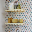 Shelves with floral wallpaper background with various kitchen and storage items.