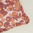 Detail of marbled cotton ruffled pillow in warm tones.