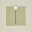 Simple metal flat slotted spoon in brass on colored paper.