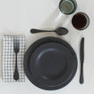 Placesetting with Stoneware Dinnerware pieces on ivory tablecloth.